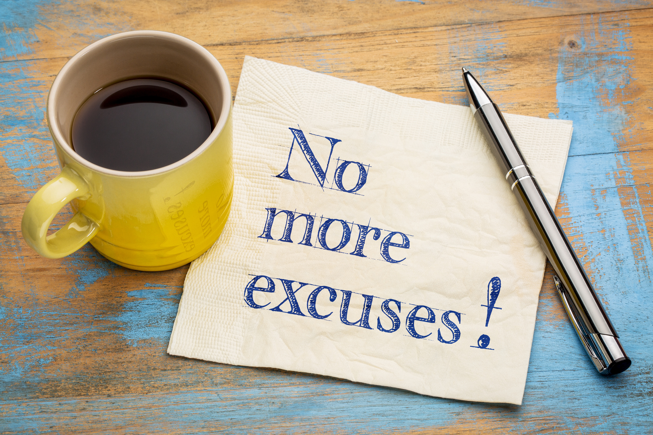 No more excuses! A motivational handwriting on a napkin with a cup of espresso coffee